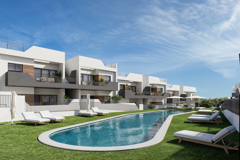 Moderne witte appartementen met zwembad, ligbedden en een groen grasveld onder een strakblauwe lucht