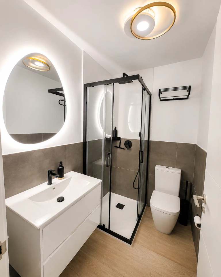 Strakke moderne badkamer met wit meubel, LED-spiegel, matzwarte kranen, inloopdouche en toilet in Casa Amparo