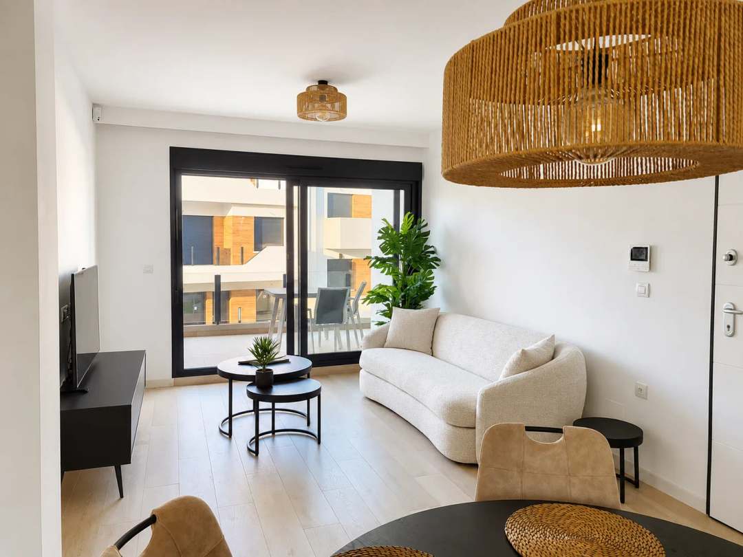 Lichte, moderne woonkamer met crèmekleurige bank, eettafel en toegang tot het balkon van Casa Amparo