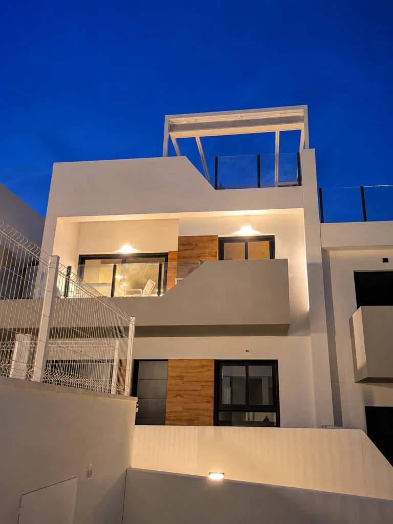 Moderne gevel van Casa Amparo bij avondlicht, met helder blauwe lucht erboven en warme verlichting